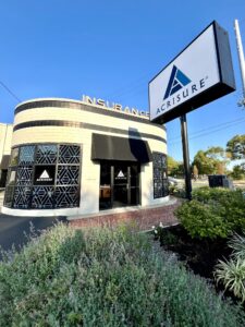 Modern architectural building with the Acrisure Insurance logo on the exterior signage under a clear blue sky.