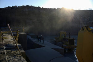 Quarry workers and heavy machinery in the limestone quarry at sunrise