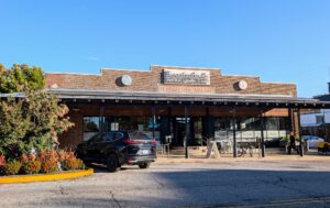 Bloomingfoods Market and Deli Near West storefront on West Sixth Street on a sunny afternoon, with its brick front and covered sidewalk