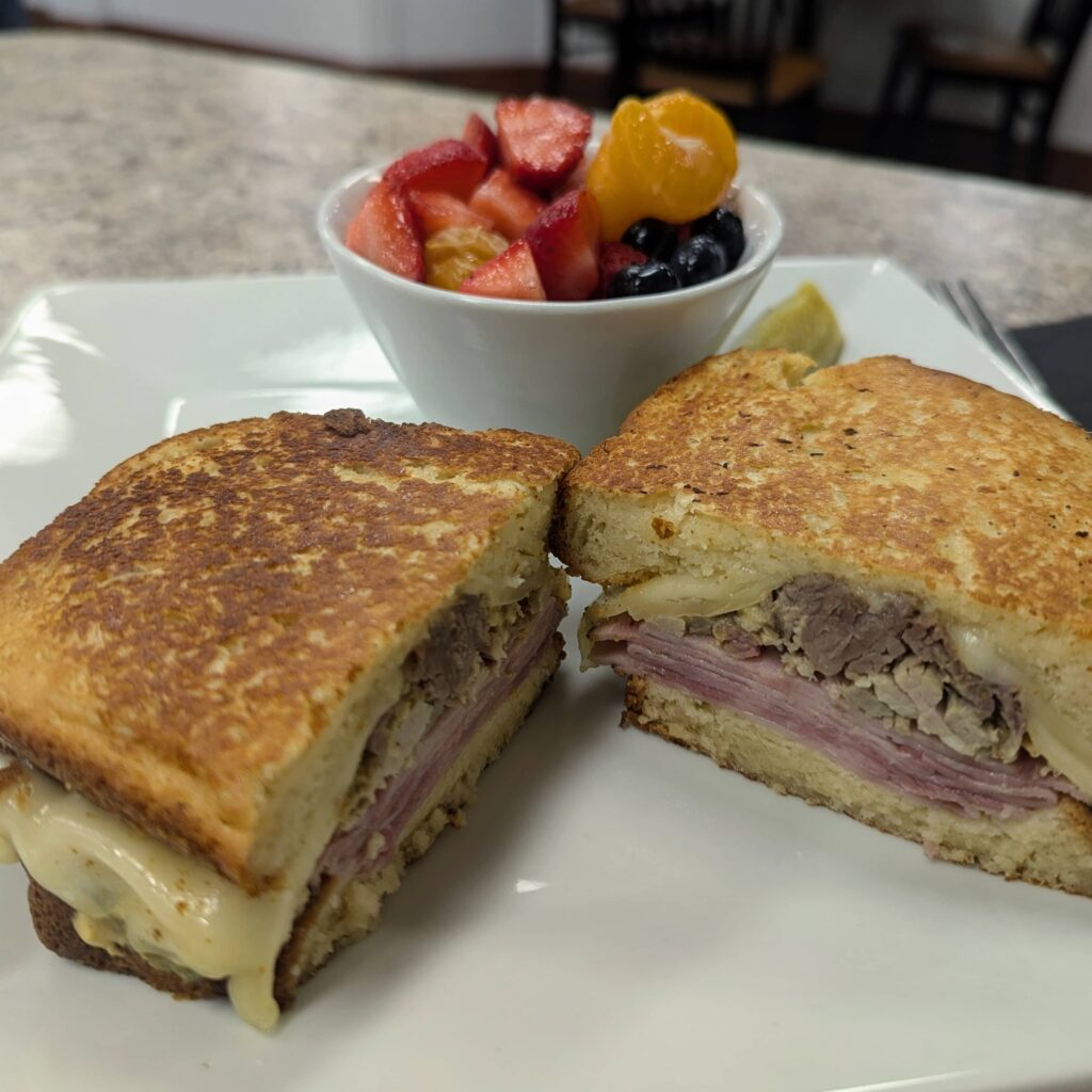 Cuban sandwich with ham, cheese, and pulled pork served with a side of fresh fruit at Brightside Cafe in Bloomington, Indiana.