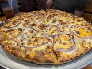 Close-up of Mother Bear’s Pizza featuring melted cheese, grilled chicken, and red onion on a golden crust, served fresh at the Campus location in Bloomington, Indiana