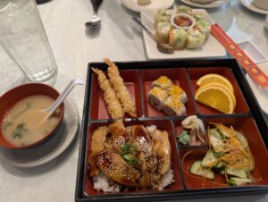 A bento box at My Thai Cafe with teriyaki chicken, shrimp tempura, sushi rolls, orange slices and miso soup