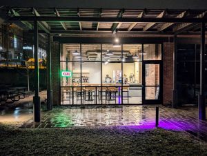 Exterior of Soma Coffeehouse & Juice Bar at night in Bloomington, Indiana with neon open sign