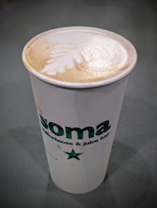 Latte with leaf latte art in a Soma Coffeehouse & Juice Bar to-go cup in Bloomington, Indiana