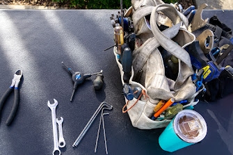 A mechanic’s canvas bag filled with bike tools laid out on a table.